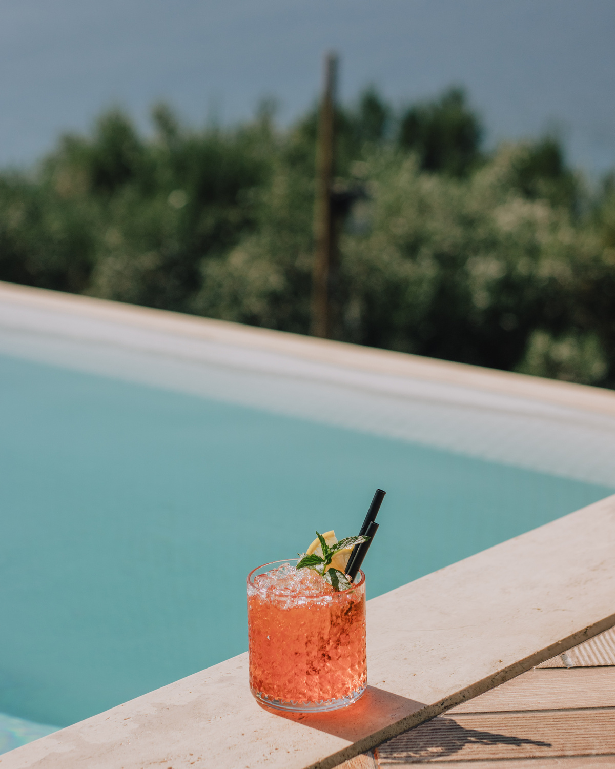 Cold Drink in Glass Against Swimming Pool